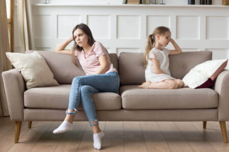 A serious mother and daughter sit facing away from each other, symbolising repeating generational trauma patterns.